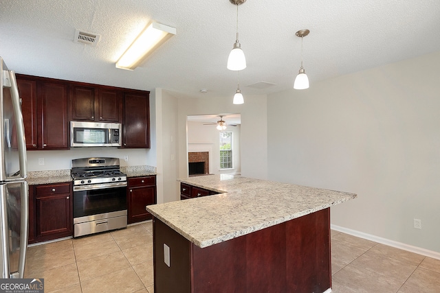 kitchen featuring a fireplace, a kitchen island, ceiling fan, stainless steel appliances, and decorative light fixtures