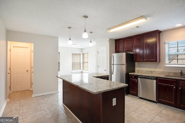 kitchen featuring a textured ceiling, stainless steel appliances, sink, and a kitchen island