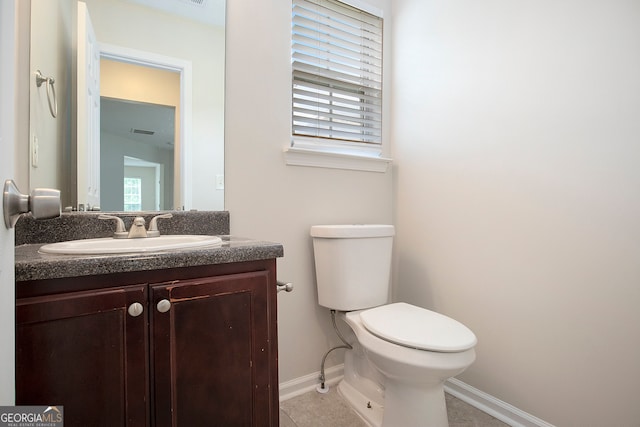 bathroom featuring toilet, vanity, tile patterned floors, and a wealth of natural light