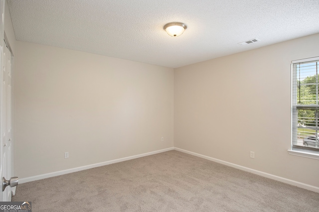 carpeted empty room with a textured ceiling