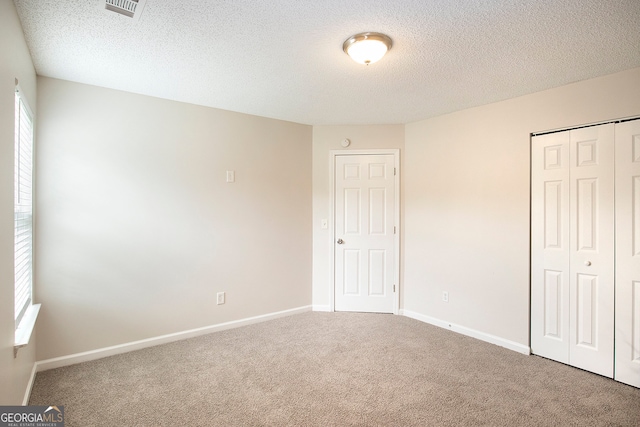 unfurnished bedroom featuring a closet, carpet flooring, and a textured ceiling