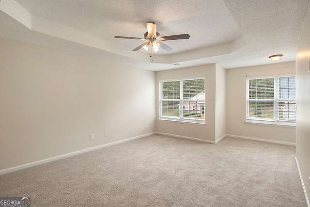 spare room with a wealth of natural light, ceiling fan, a textured ceiling, and a raised ceiling