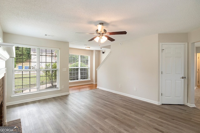 unfurnished living room featuring dark wood-type flooring, ceiling fan, and a textured ceiling