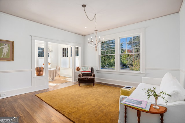 sitting room with hardwood / wood-style floors and a notable chandelier