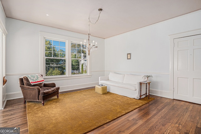 sitting room with dark wood-type flooring, crown molding, and an inviting chandelier