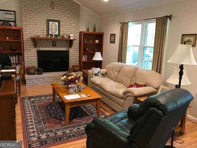 living room featuring light hardwood / wood-style flooring, a fireplace, crown molding, and vaulted ceiling