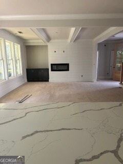 unfurnished living room featuring baseboards, beam ceiling, and a glass covered fireplace