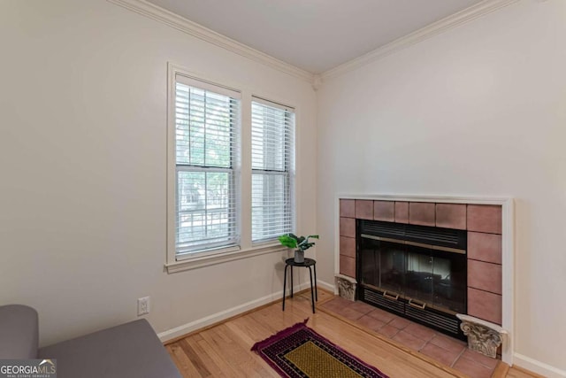 sitting room with ornamental molding, light wood-type flooring, and a fireplace