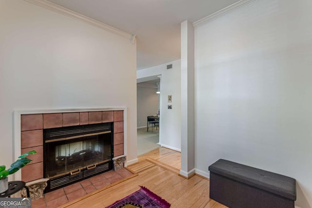 living room with crown molding, a fireplace, and light hardwood / wood-style floors