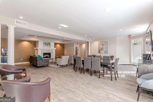 dining space with ornate columns and light hardwood / wood-style flooring