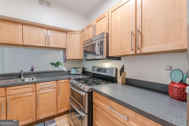 kitchen featuring appliances with stainless steel finishes, sink, and light brown cabinetry