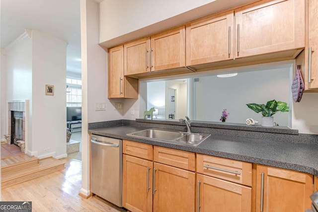 kitchen with sink, a brick fireplace, stainless steel dishwasher, ornamental molding, and light hardwood / wood-style flooring