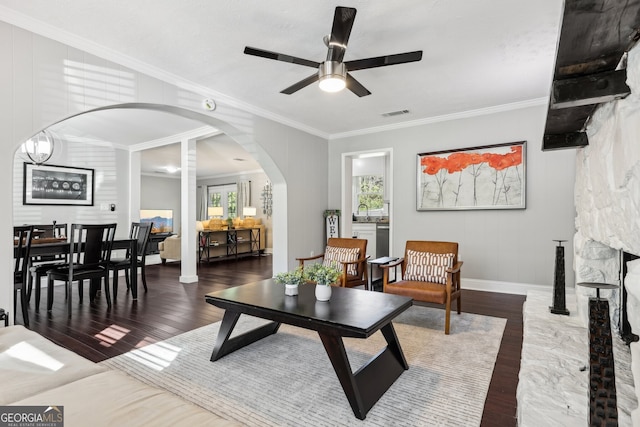 living room featuring dark wood-type flooring, ceiling fan, ornamental molding, and plenty of natural light