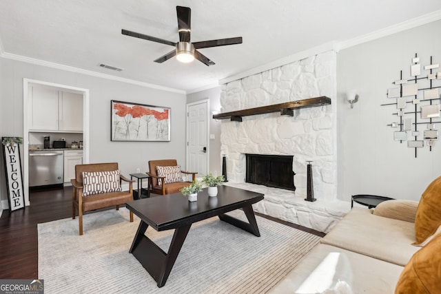 living room featuring ceiling fan, hardwood / wood-style flooring, ornamental molding, and a fireplace