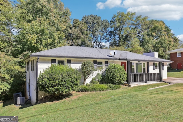 ranch-style home with central air condition unit and a front lawn