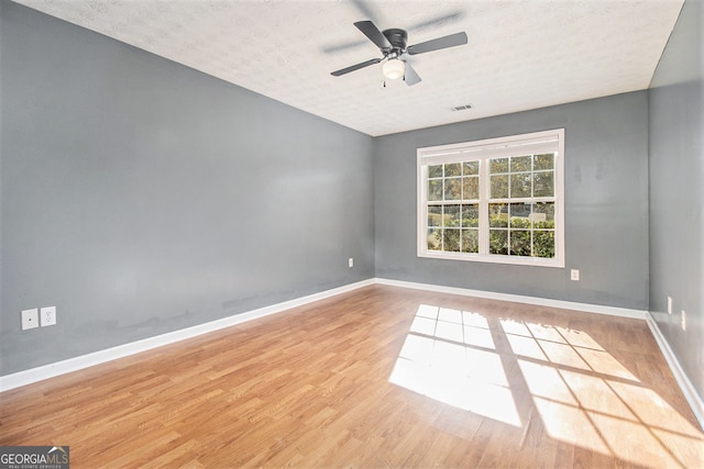 empty room with ceiling fan, a textured ceiling, and light hardwood / wood-style flooring