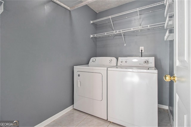 clothes washing area featuring washer and dryer and light tile patterned floors