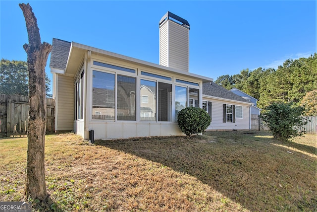 back of property with a lawn and a sunroom