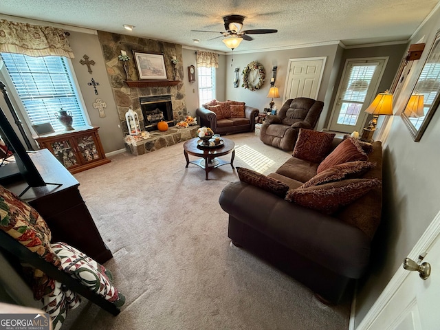 carpeted living room with a stone fireplace, ornamental molding, a textured ceiling, and ceiling fan