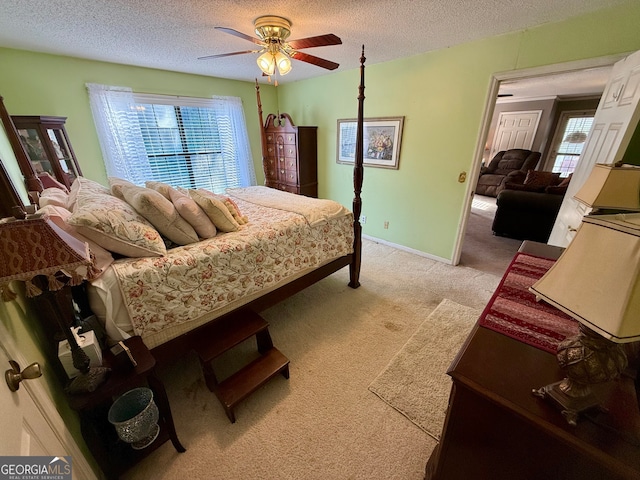 bedroom featuring a textured ceiling, light colored carpet, and ceiling fan