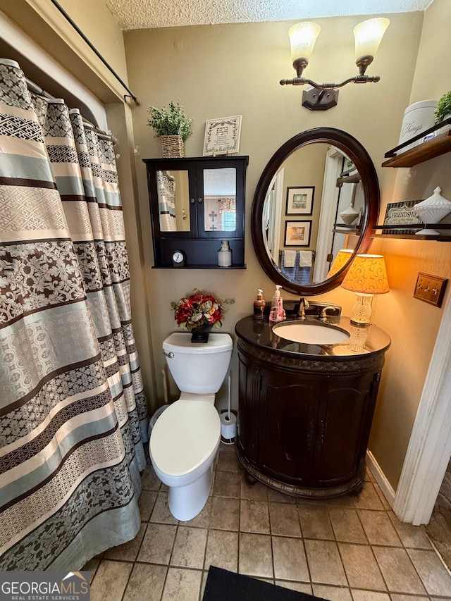 bathroom with vanity, a textured ceiling, toilet, and tile patterned flooring