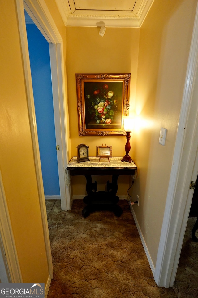 hallway featuring crown molding and dark colored carpet