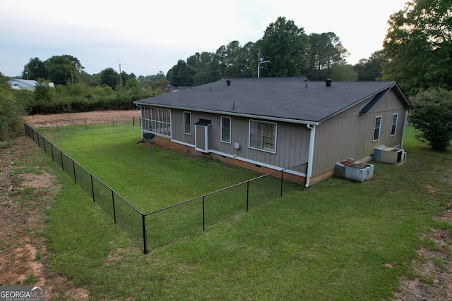 rear view of house featuring central AC and a yard