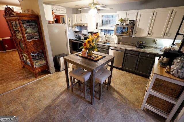 kitchen featuring sink, white cabinetry, appliances with stainless steel finishes, light stone counters, and ceiling fan