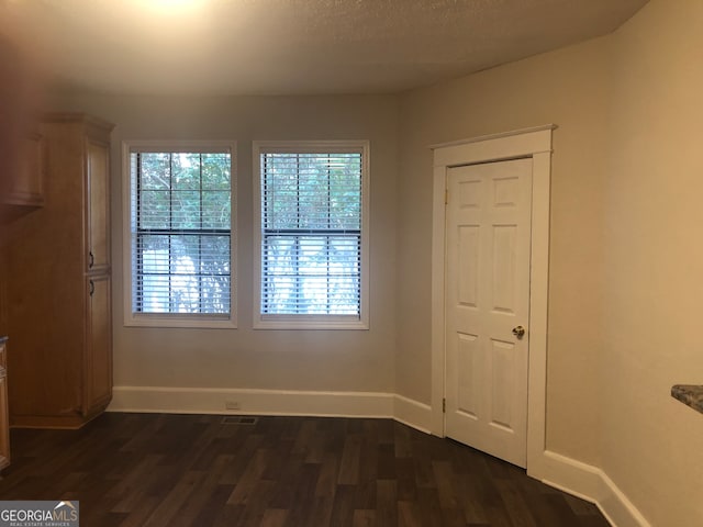 spare room with dark hardwood / wood-style floors and a textured ceiling