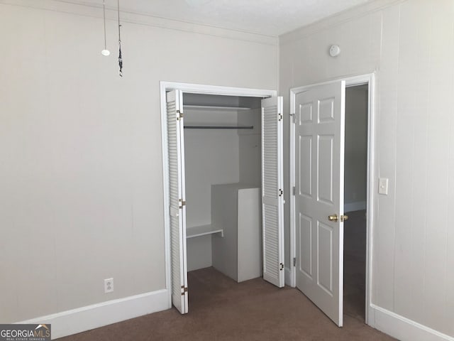 unfurnished bedroom featuring a closet, crown molding, wood walls, and carpet flooring