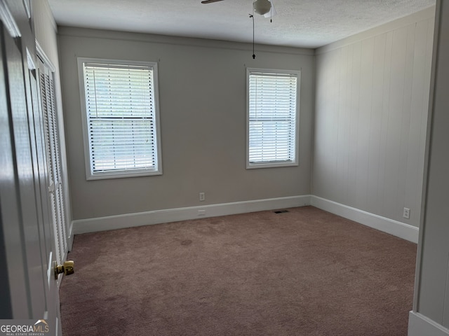 empty room featuring a textured ceiling, carpet, and ceiling fan