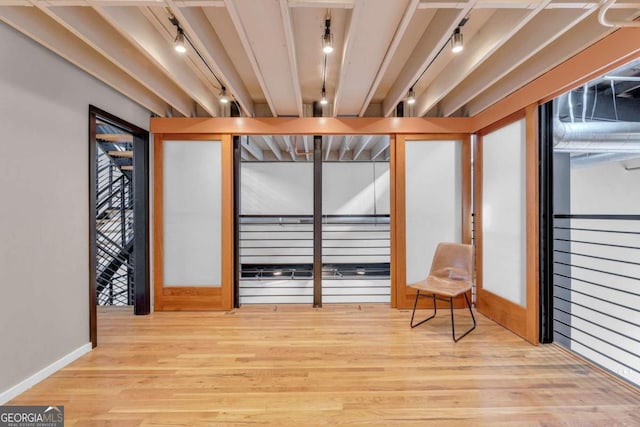 living area with beamed ceiling, track lighting, and light wood-type flooring