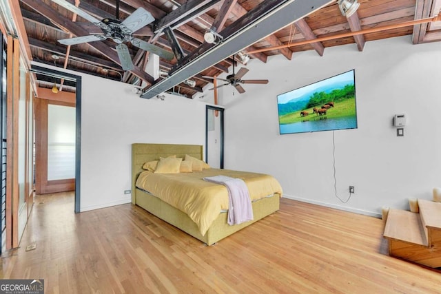 bedroom with ceiling fan, lofted ceiling with beams, and hardwood / wood-style floors