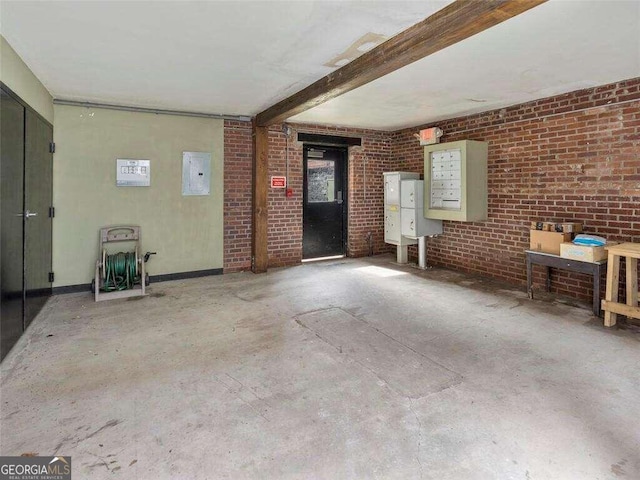 unfurnished living room with beamed ceiling, concrete floors, and brick wall