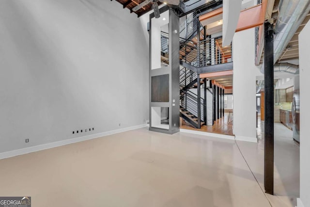 unfurnished living room featuring a high ceiling and concrete flooring