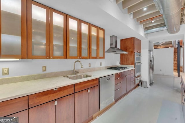 kitchen with light stone counters, sink, appliances with stainless steel finishes, and wall chimney range hood