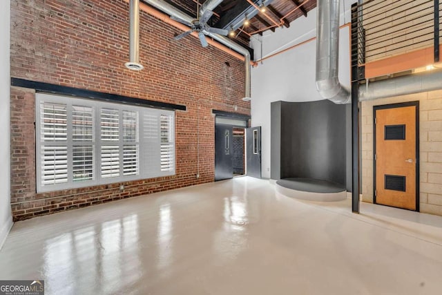 interior space featuring brick wall, concrete flooring, and a towering ceiling