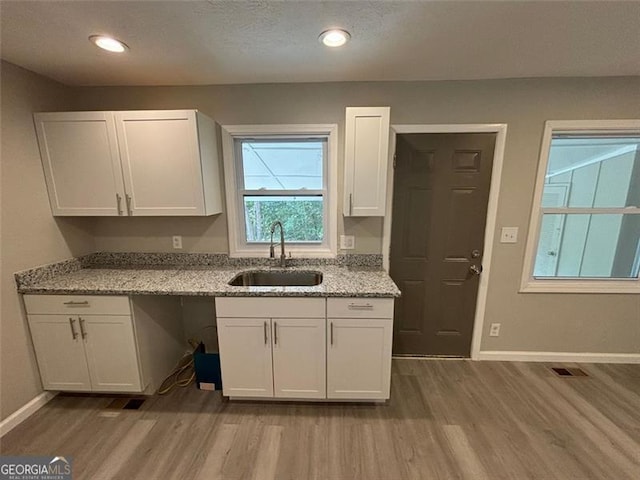 kitchen with light hardwood / wood-style flooring, sink, and white cabinets