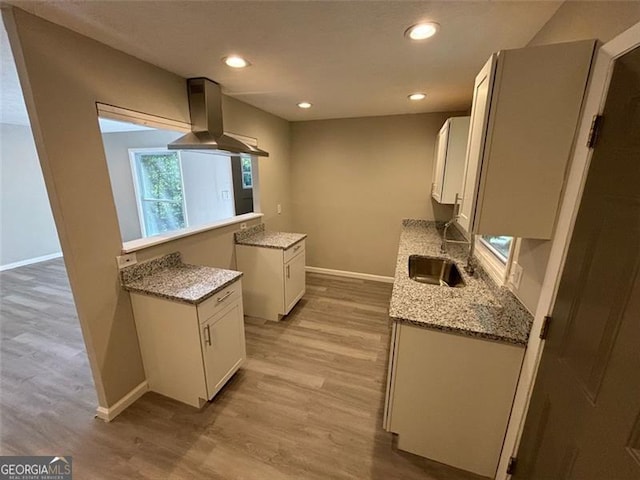 kitchen featuring light stone countertops, sink, white cabinetry, extractor fan, and light hardwood / wood-style flooring