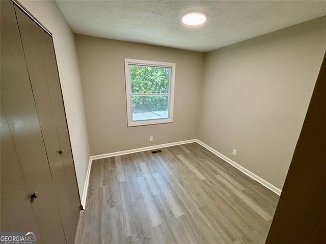 unfurnished bedroom featuring a closet, light hardwood / wood-style floors, and a textured ceiling