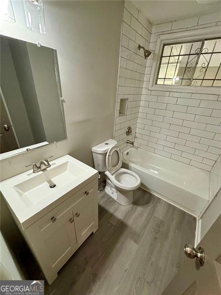 full bathroom featuring vanity, toilet, tiled shower / bath combo, and wood-type flooring