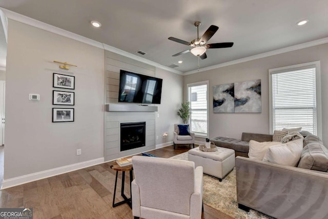 living room featuring ornamental molding, hardwood / wood-style floors, a fireplace, and ceiling fan