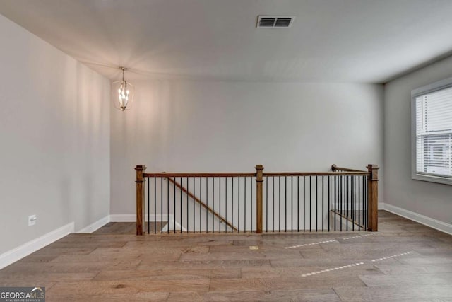 spare room featuring baseboards, wood finished floors, and visible vents