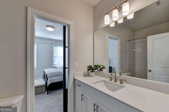 bathroom with toilet, vanity, and tiled shower