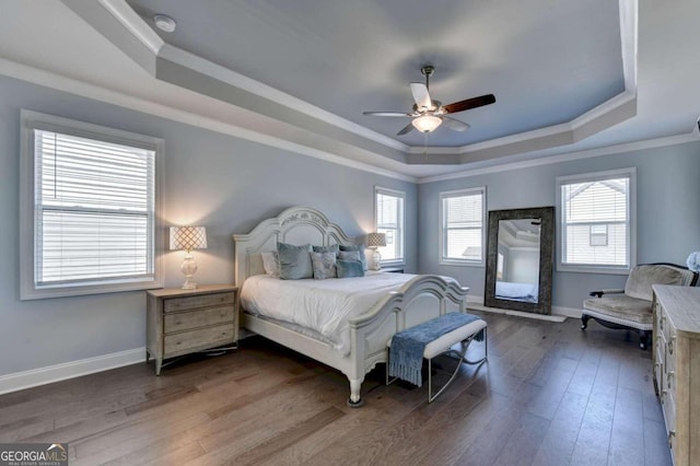 bedroom with a raised ceiling, a ceiling fan, crown molding, baseboards, and hardwood / wood-style flooring
