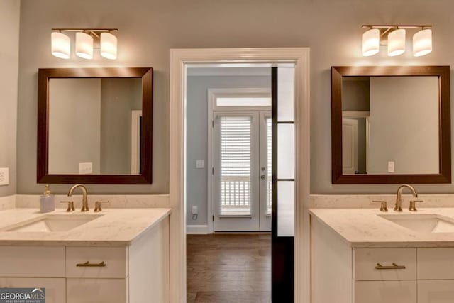full bath featuring two vanities, wood finished floors, and a sink