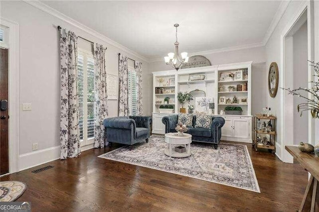 living area with dark hardwood / wood-style floors, ornamental molding, and an inviting chandelier