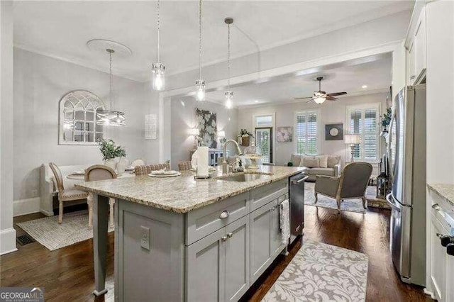 kitchen with sink, stainless steel appliances, dark hardwood / wood-style floors, pendant lighting, and a center island with sink