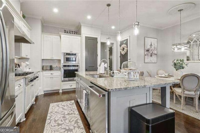 kitchen featuring a kitchen island with sink, sink, light stone countertops, white cabinetry, and stainless steel appliances