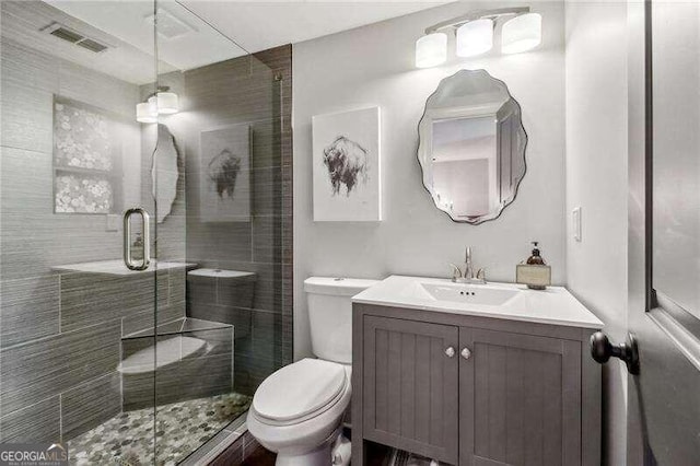 bathroom featuring vanity, toilet, and a shower with shower door